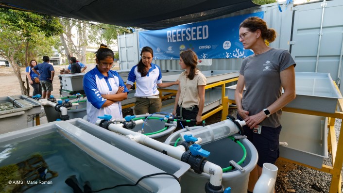 many people gathered around large tanks with ReefSeed banner in background