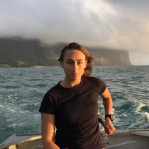 Woman in boat on the water wearing black shirt, with island in background