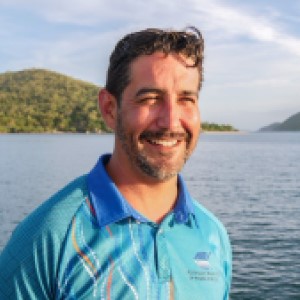 Man wearing blue shirt in front of island and ocean