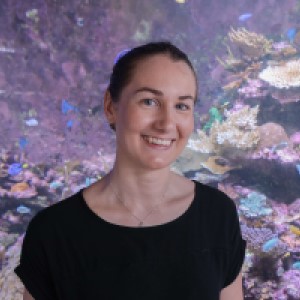 woman wearing black shirt standing in front of image of Coral Reef