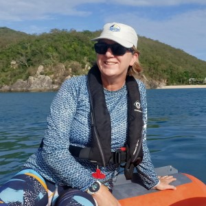 Woman on boat wearing white hat and blue long sleeved shirt