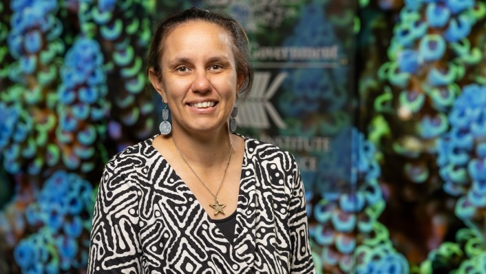 A potriat image of a woman smiling at the camera with a colourful background