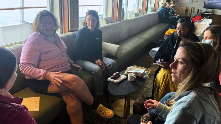 six women are sitting in a group clearly listening to one person talking.