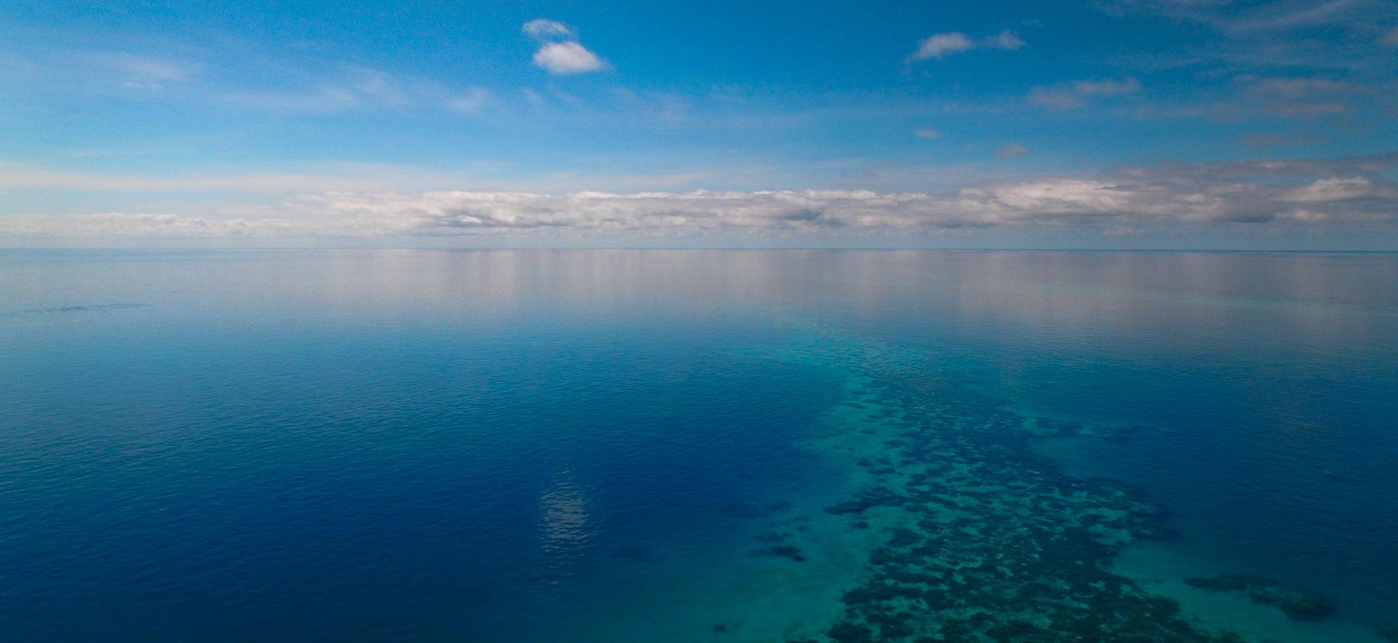 a sky with white clouds meets a calm sea