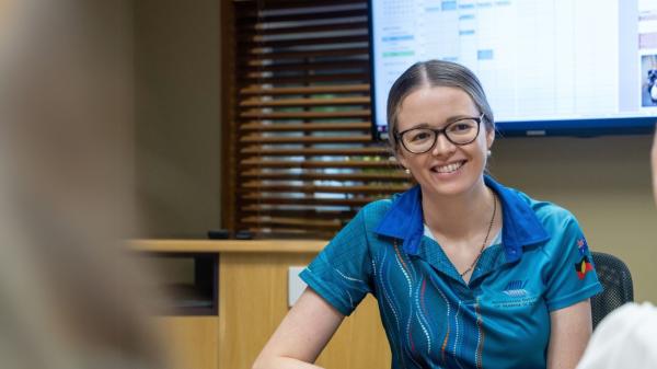 smiling woman in corporate style room looking at another person